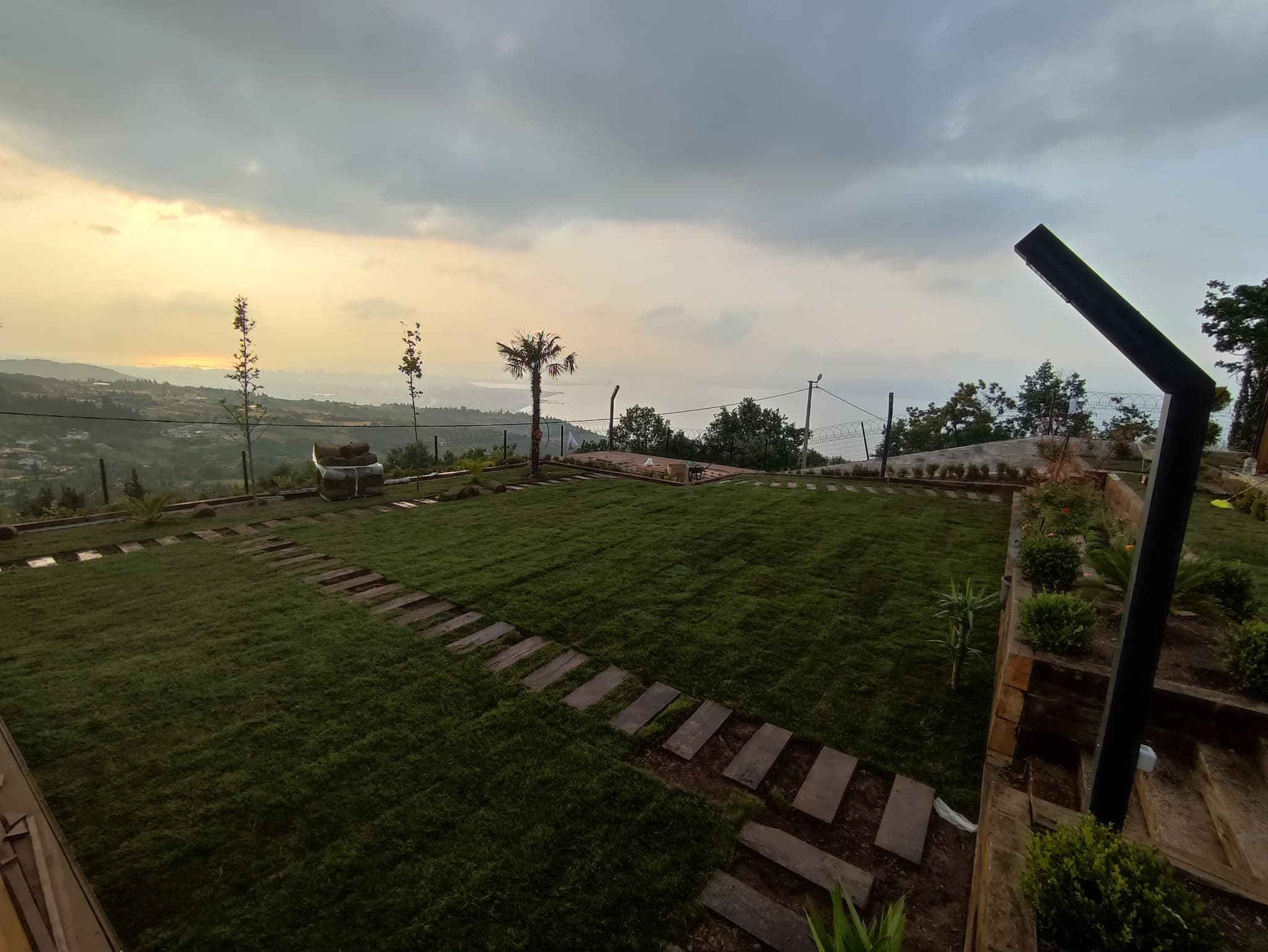 Bahçe aydınlatma elemanları bulunan gün batımındaki çim alan
